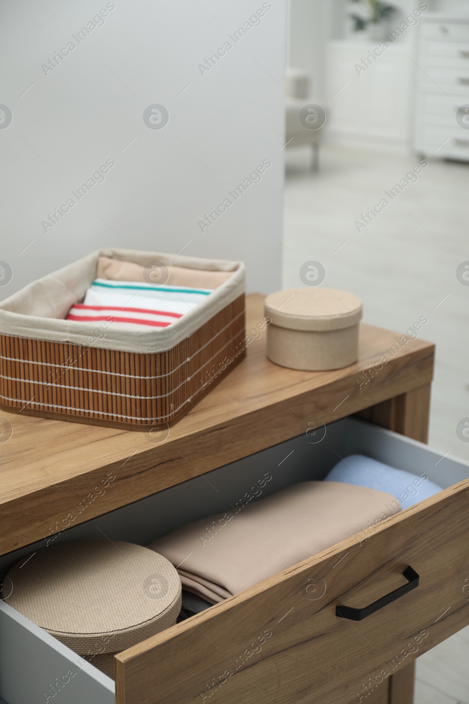 Photo of Chest of drawers with different folded clothes and accessories indoors, closeup