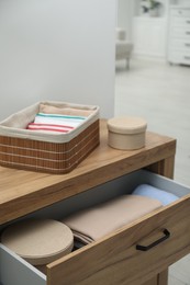 Chest of drawers with different folded clothes and accessories indoors, closeup