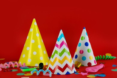 Colorful party hats and other festive items on red background