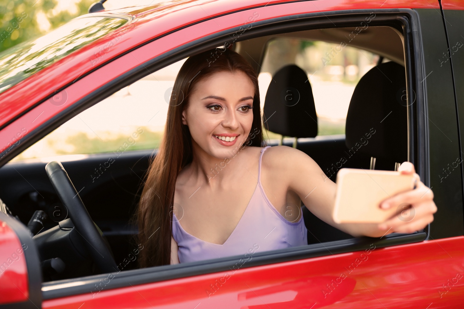 Photo of Beautiful young woman taking selfie in car