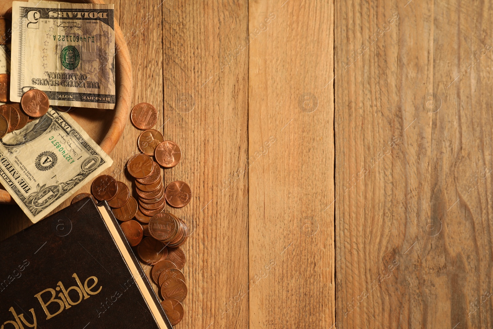 Photo of Donate and give concept. Coins, Bible and dollar banknotes on wooden table, flat lay. Space for text