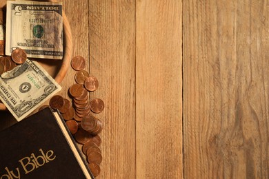 Photo of Donate and give concept. Coins, Bible and dollar banknotes on wooden table, flat lay. Space for text