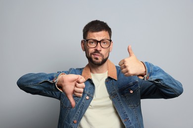 Photo of Man showing thumbs up and down on grey background