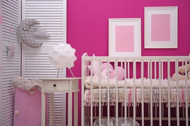 Photo of Baby room interior with crib near color wall