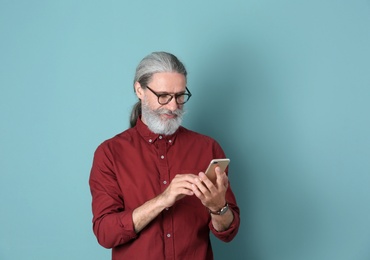 Photo of Handsome mature man with mobile phone on color background