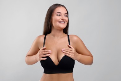 Photo of Portrait of young woman with beautiful breast on light grey background