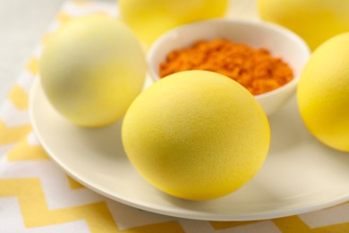 Yellow Easter eggs painted with natural dye and turmeric powder in bowl on table, closeup