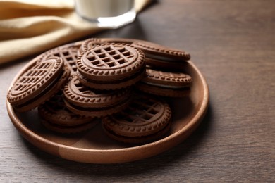 Tasty chocolate sandwich cookies with cream on wooden table