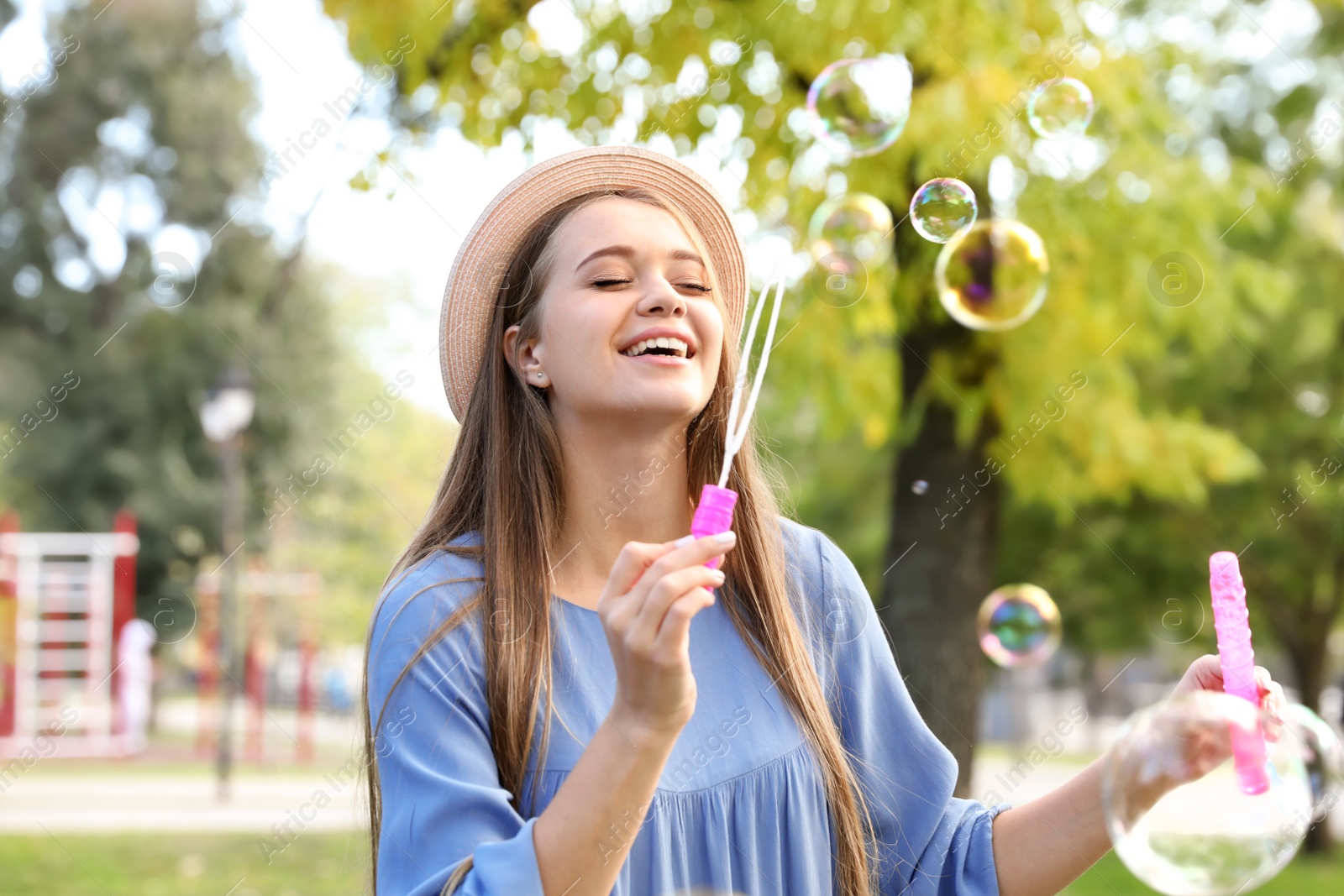 Photo of Young woman blowing soap bubbles in park