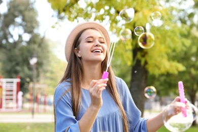 Photo of Young woman blowing soap bubbles in park