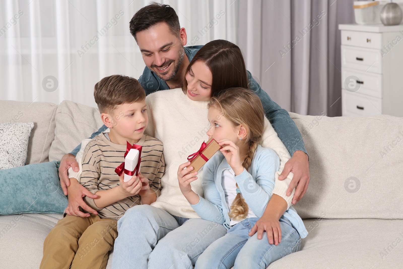 Photo of Happy family presenting each other with gifts on sofa at home