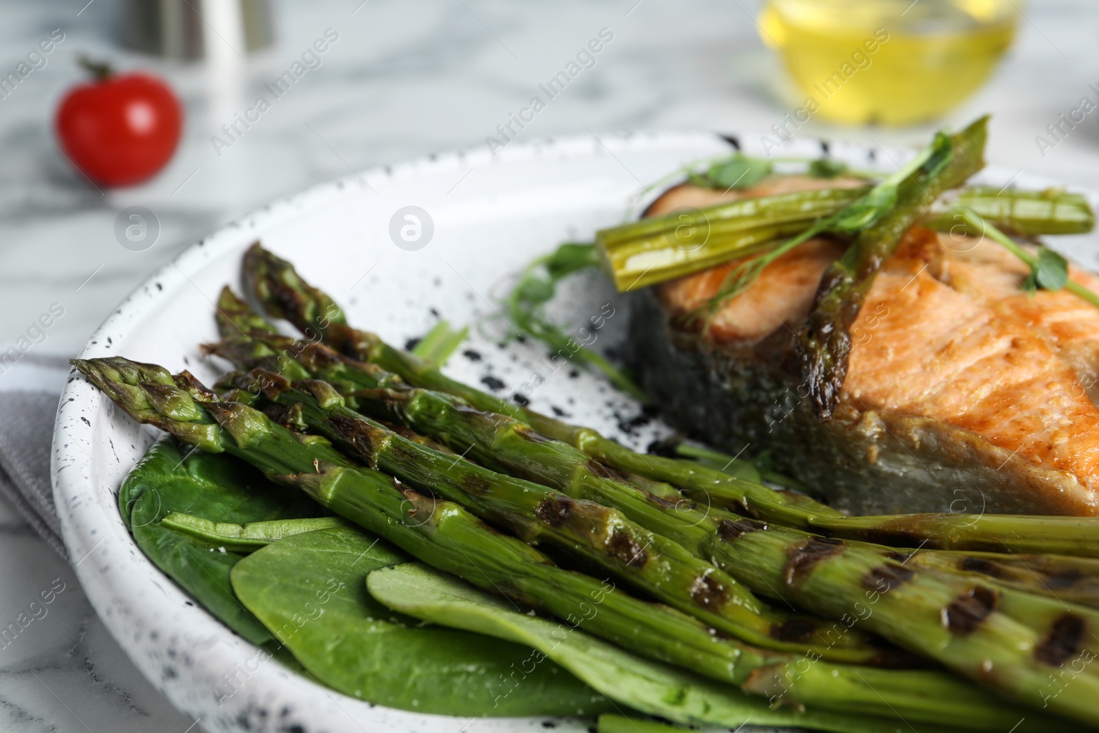 Photo of Tasty salmon steak served with grilled asparagus on plate, closeup