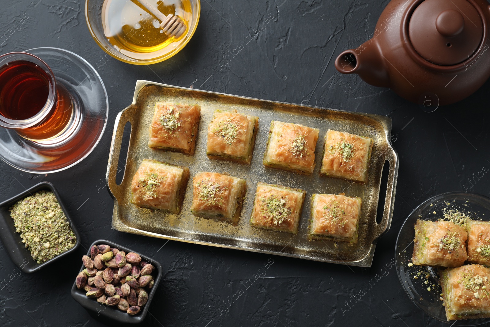 Photo of Delicious fresh baklava with chopped nuts served on grey textured table, flat lay. Eastern sweets