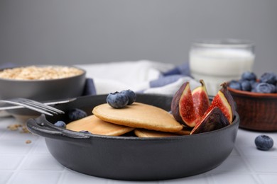 Photo of Tasty oatmeal pancakes on white tiled table, closeup