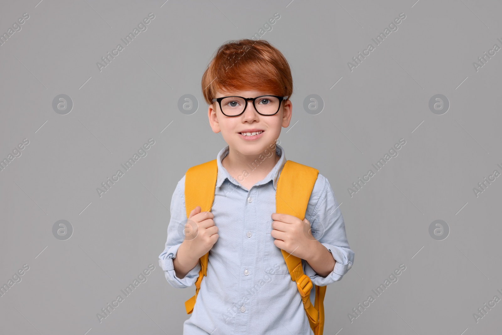 Photo of Happy schoolboy with backpack on grey background