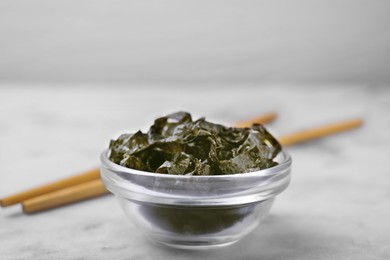 Chopped nori sheets with chopsticks on white marble table, closeup