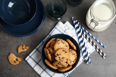 Photo of Flat lay composition with bowl of tasty chocolate chip cookies on grey table