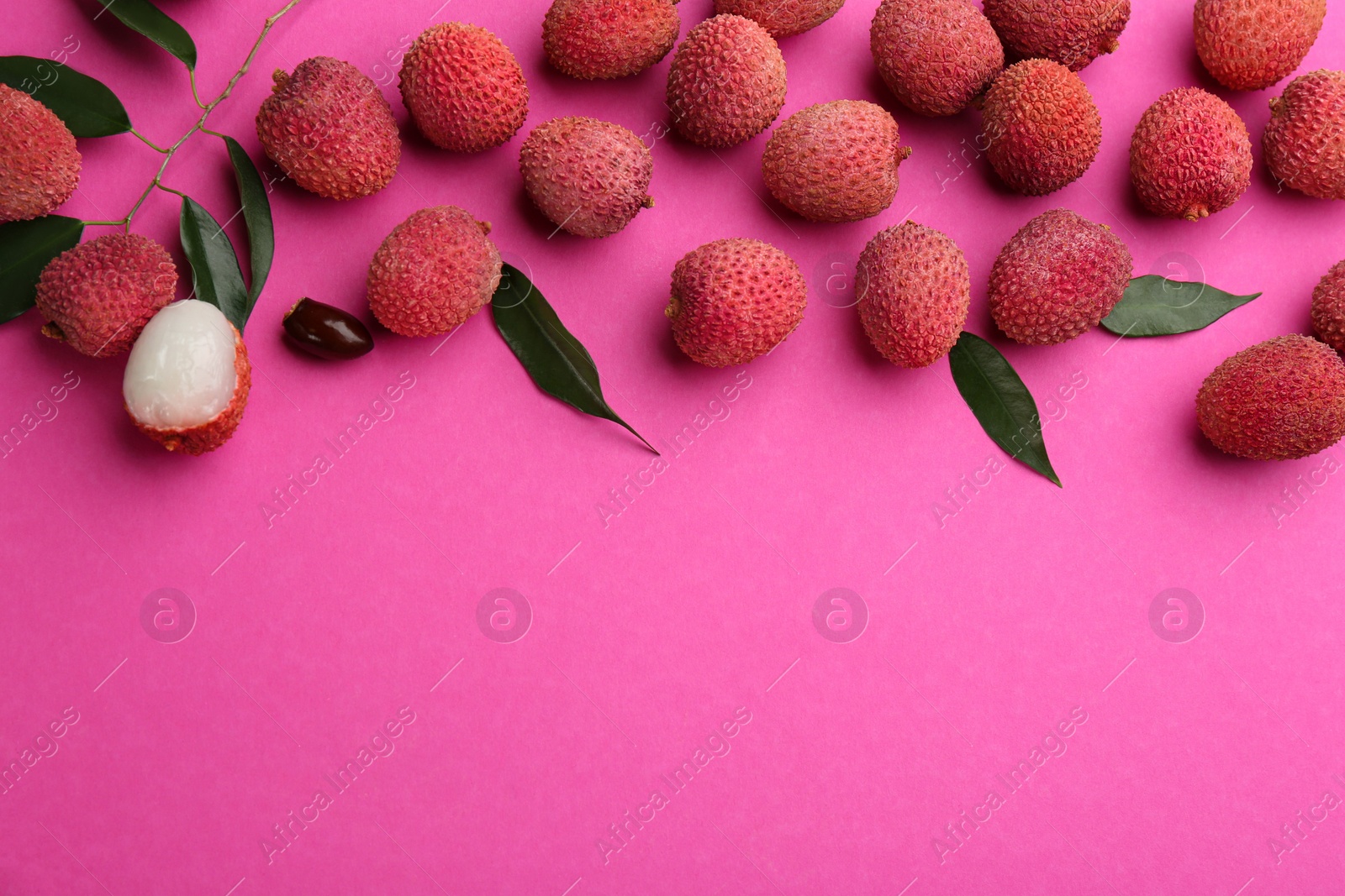 Photo of Fresh ripe lychees with leaves on pink background, flat lay. Space for text