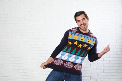 Photo of Portrait of happy man in Christmas sweater near white brick wall