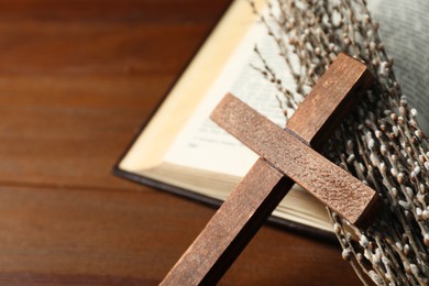 Bible, willow branches and cross on wooden table, closeup. Space for text