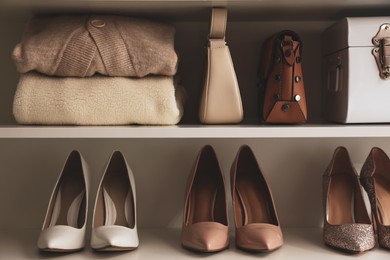 Photo of Stylish women's shoes, clothes and bags on shelving unit