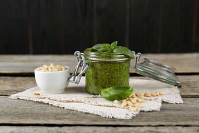 Delicious pesto sauce, pine nuts and basil leaves on wooden table