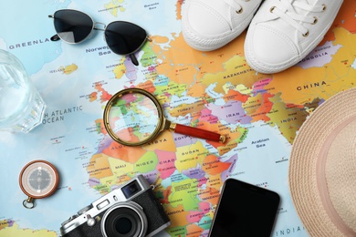 Photo of Flat lay composition with different travel accessories on world map. Planning summer vacation trip