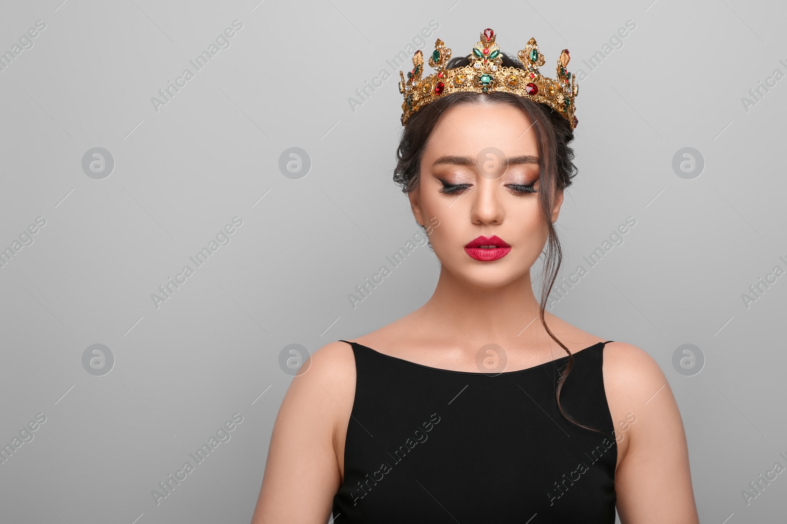 Photo of Beautiful young woman wearing luxurious crown on light grey background, space for text