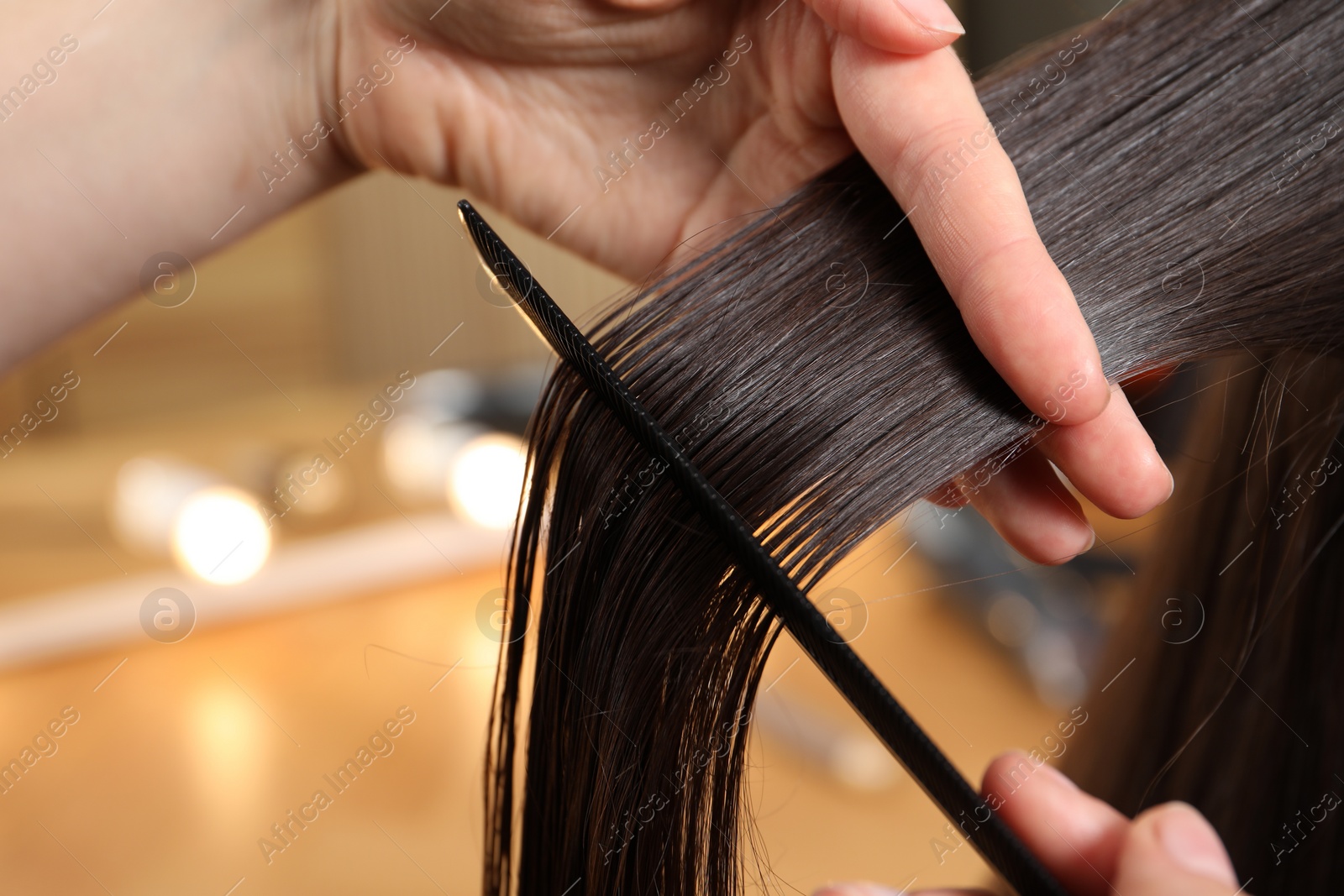 Photo of Hairdresser combing client's hair in salon, closeup