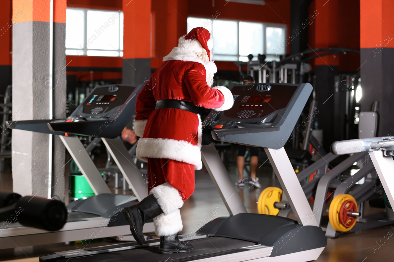 Photo of Authentic Santa Claus training on treadmill in modern gym