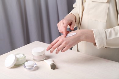 Woman applying hand cream at home, closeup