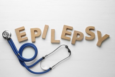 Photo of Word Epilepsy and stethoscope on white wooden background, flat lay
