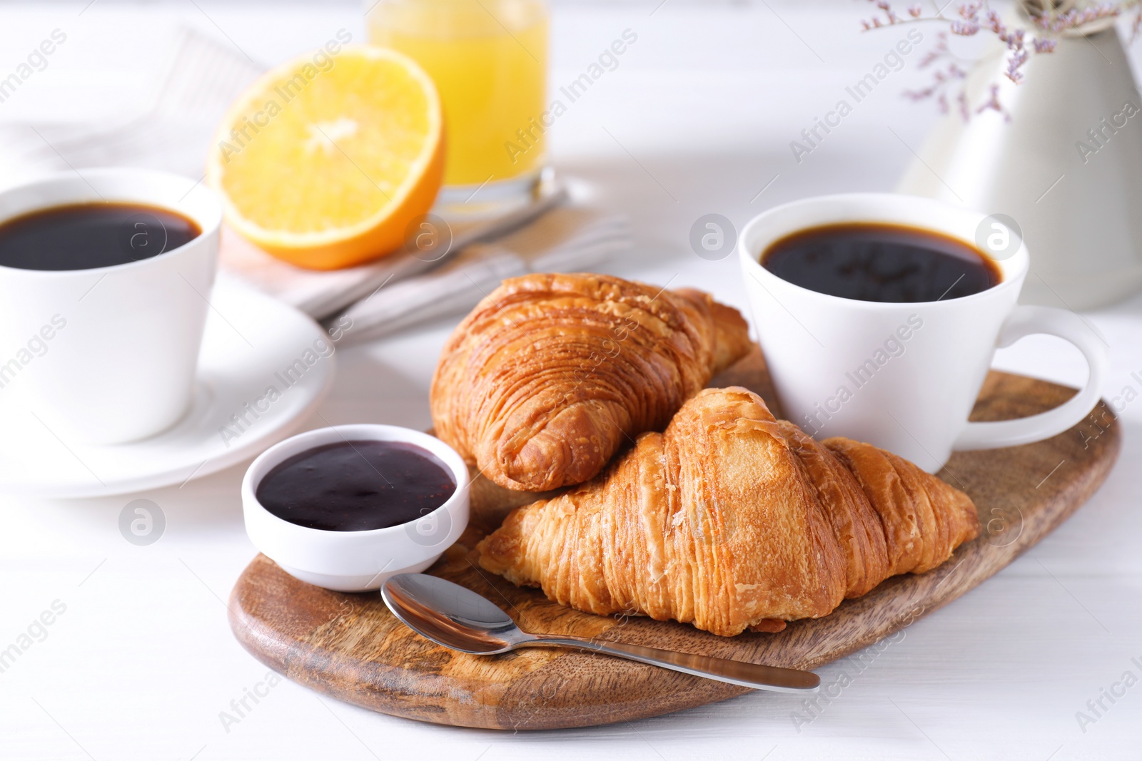 Photo of Tasty breakfast. Cup of coffee, jam and croissants on white wooden table