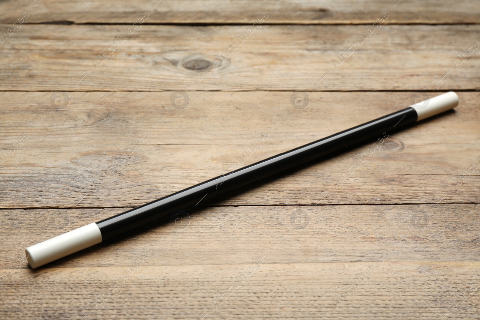 Photo of Beautiful black magic wand on wooden table
