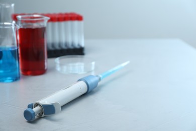 Laboratory analysis. Micropipette, beakers with liquids, petri dish and test tubes on grey table, space for text