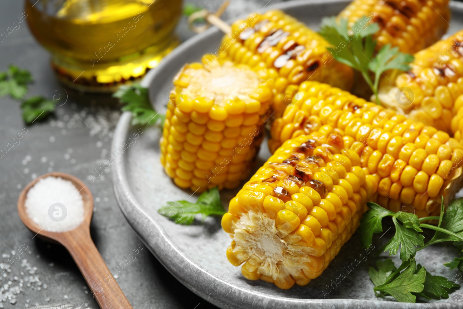 Photo of Delicious grilled corn cobs on grey table, closeup