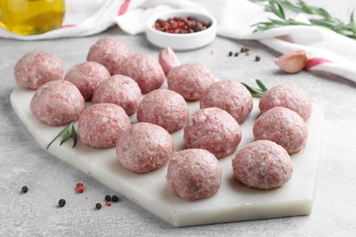 Many fresh raw meatballs on light grey table