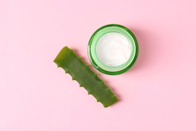 Jar of natural gel and cut aloe on pink background, top view