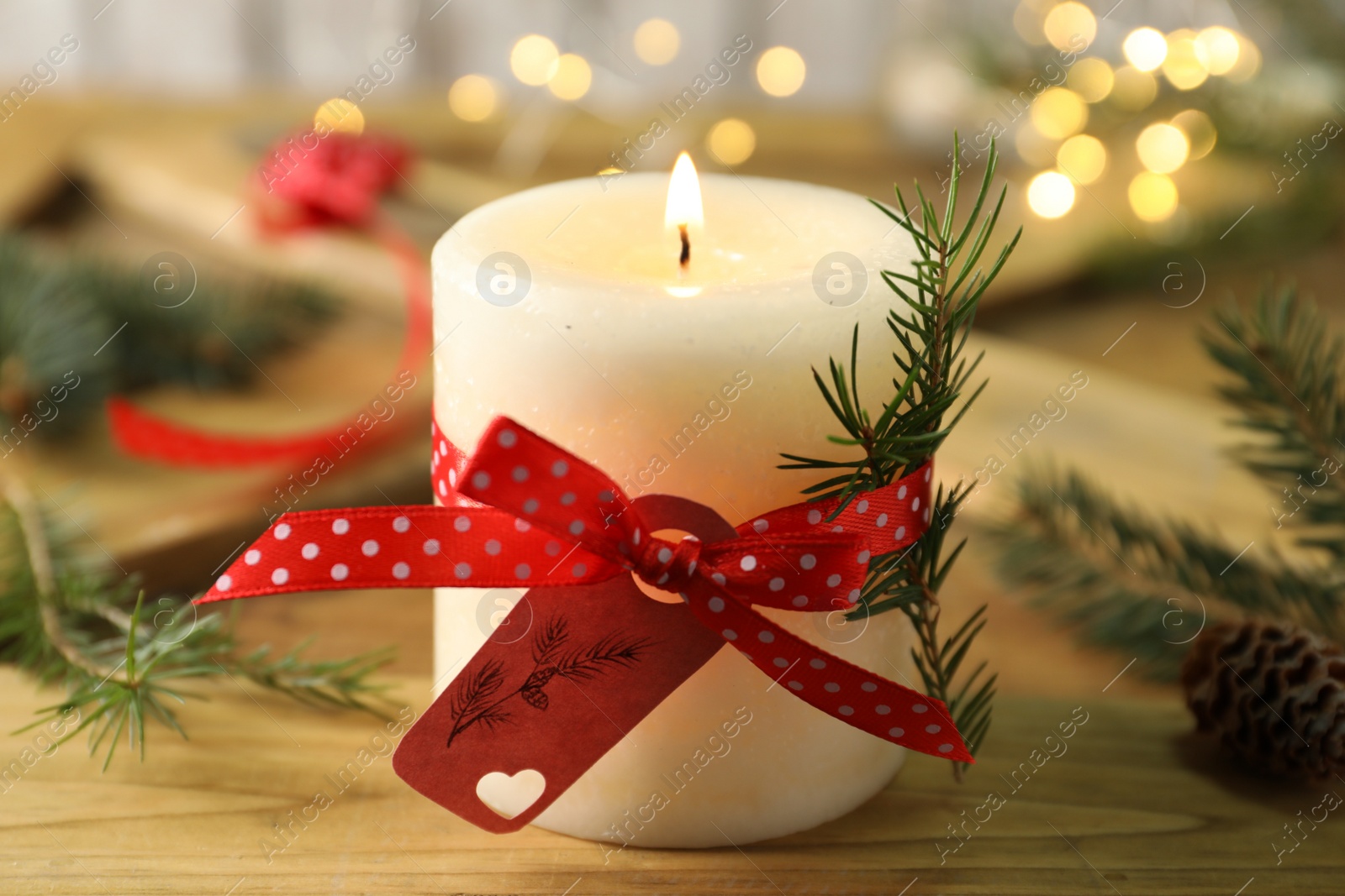 Photo of Burning candle with pinecone scent on wooden table, closeup