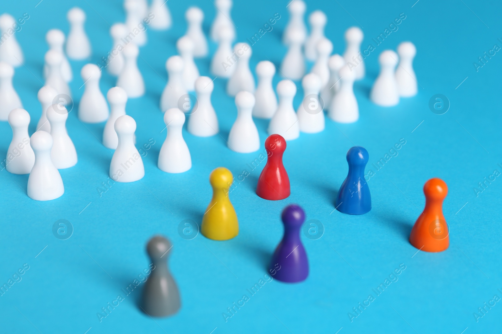 Photo of Colorful pawns on light blue background. Social inclusion concept