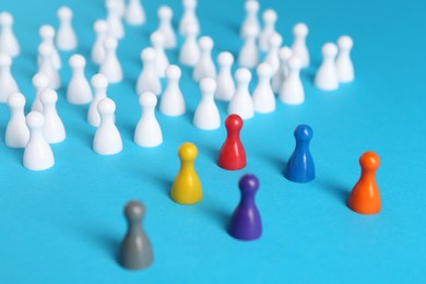 Photo of Colorful pawns on light blue background. Social inclusion concept