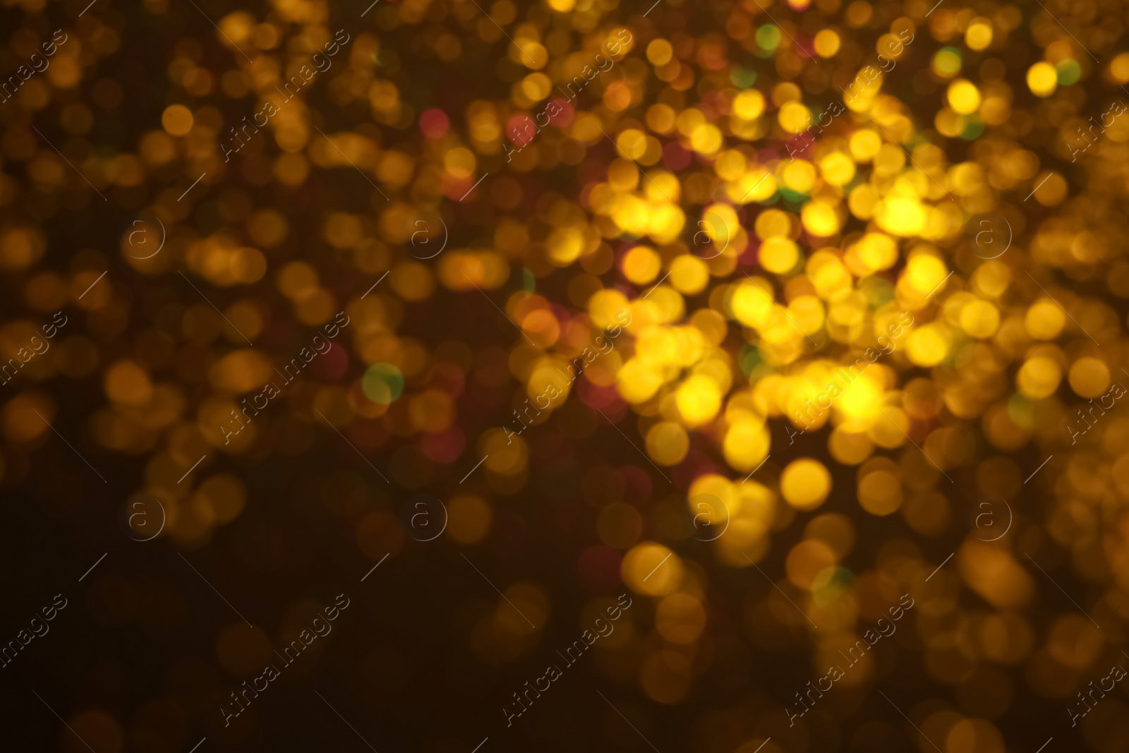 Photo of Blurred view of golden glitter on dark background. Bokeh effect