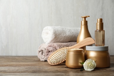 Different hair products, towel and brush on wooden table. Space for text