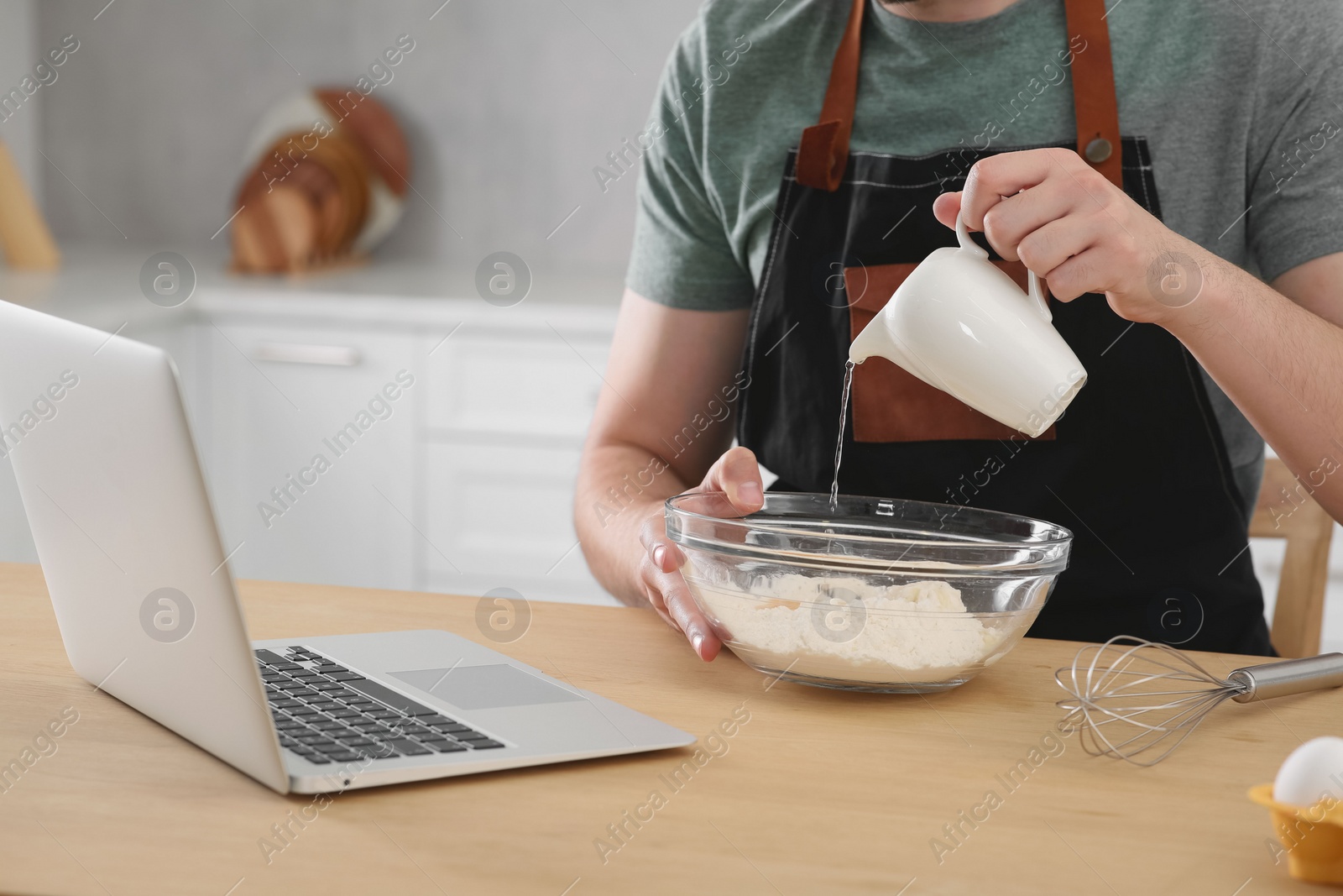 Photo of Man learning to cook with online video at wooden table in kitchen, closeup. Time for hobby