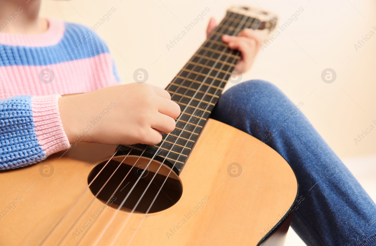 Photo of Little girl playing wooden guitar, closeup view