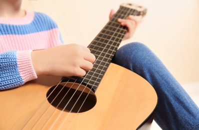 Little girl playing wooden guitar, closeup view