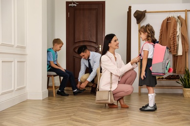 Photo of Parents helping their children get ready for school in hallway