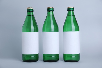 Glass bottles with soda water on light background