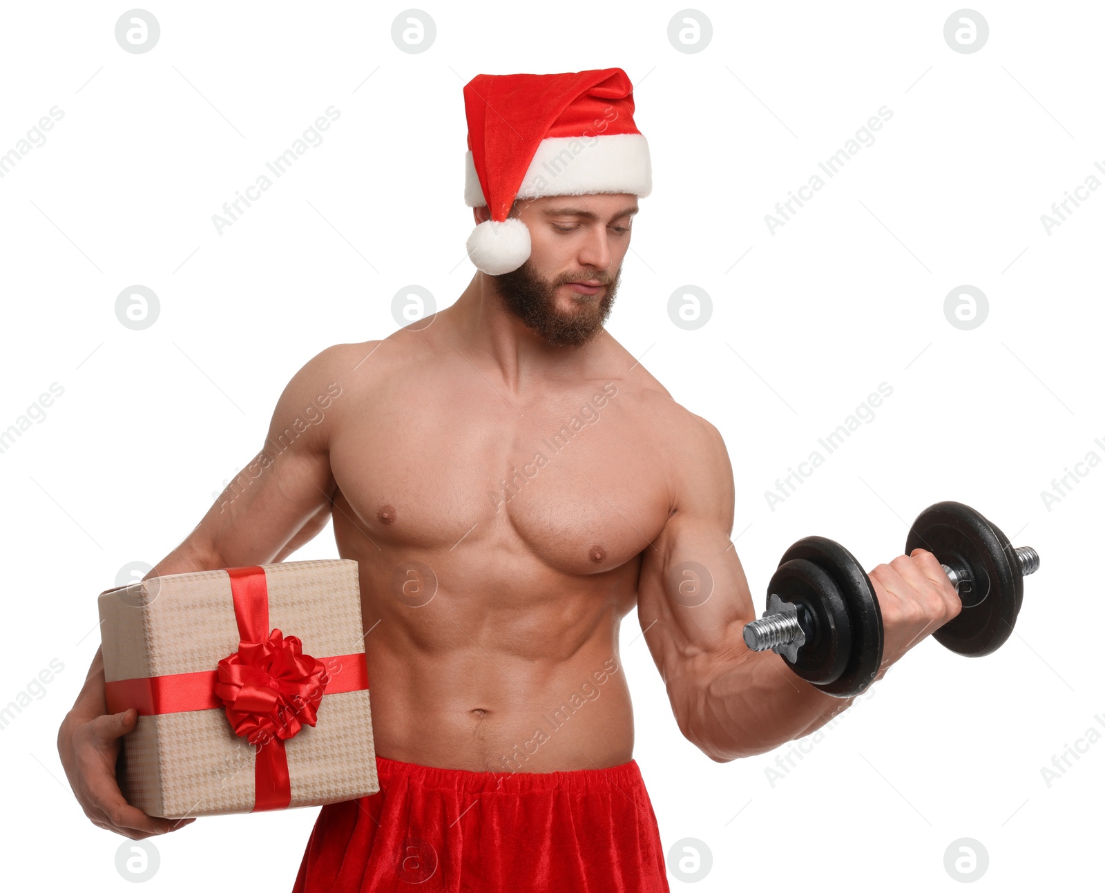 Photo of Attractive young man with muscular body in Santa hat holding Christmas gift box and dumbbell on white background