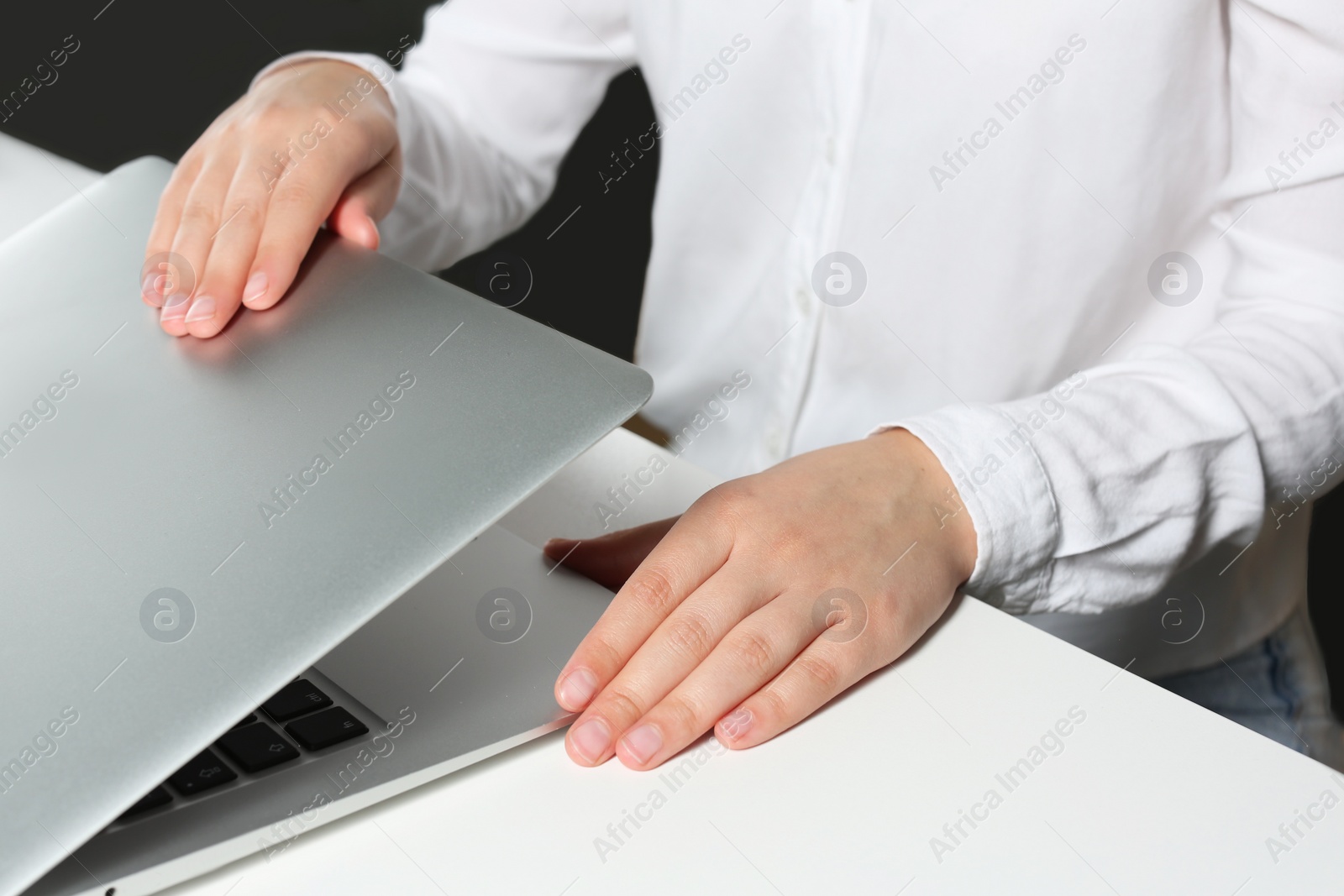 Photo of Woman opening laptop at white table in office, closeup
